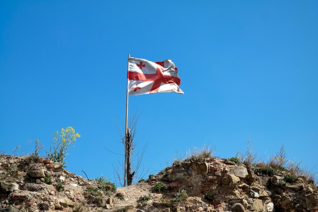 Le drapeau géorgien flottant dans le vent contre le ciel bleu