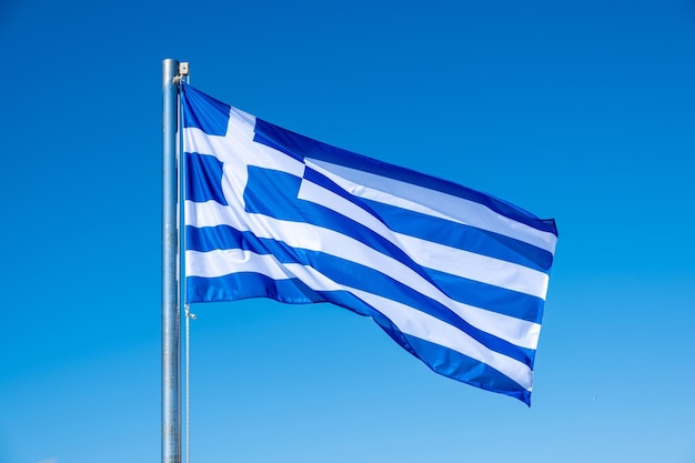 Le drapeau grec agitant sur le fond bleu du ciel