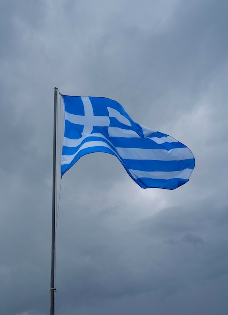 Un drapeau grec bleu et blanc vole sur fond de ciel orageux et de nuages