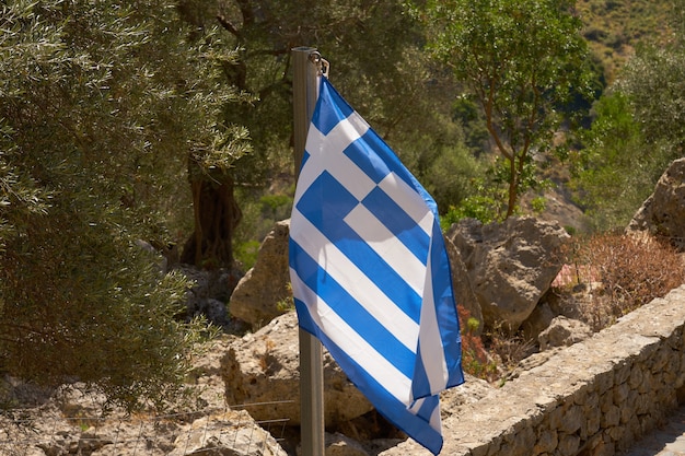 Drapeau de la Grèce dans les montagnes près du mur de pierre.