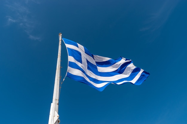 Drapeau de la Grèce sur mât contre le ciel bleu
