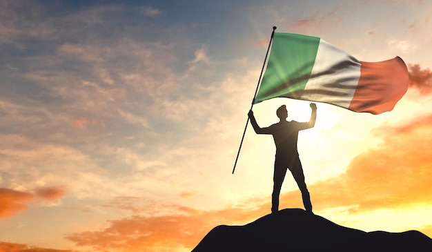 Drapeau de l'Irlande agité par un homme célébrant le succès au sommet d'une montagne 3D Rendering