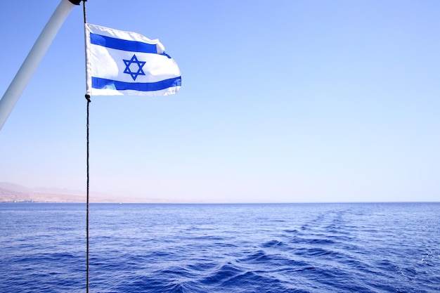 Photo le drapeau d'israël dans le vent, la mer rouge en arrière-plan