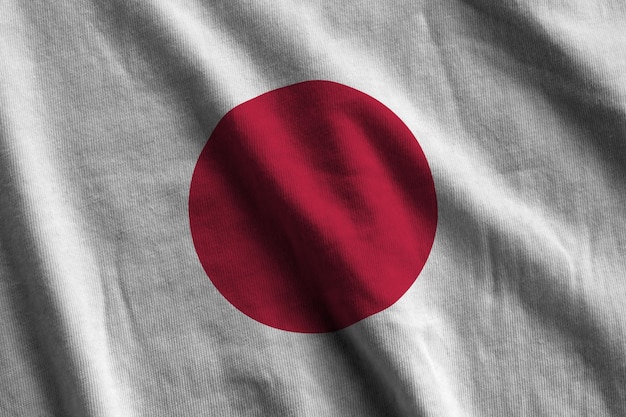 Drapeau japonais avec de grands plis agitant de près sous la lumière du studio à l'intérieur Les symboles officiels et les couleurs de la bannière