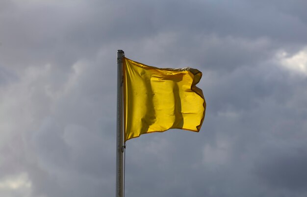 le drapeau jaune vole dans l'air avec des nuages