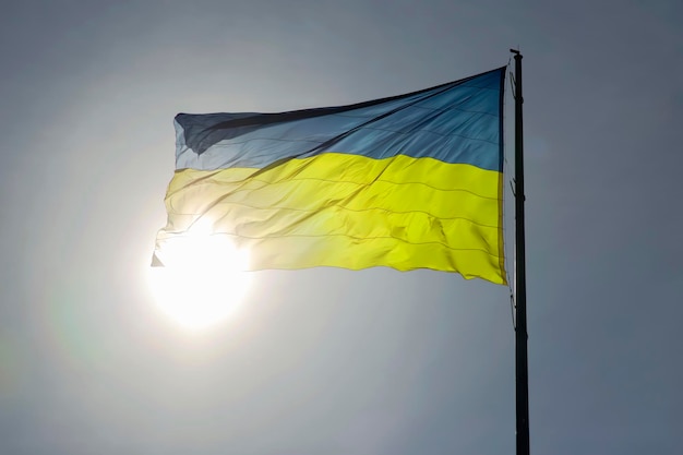 Le drapeau national du pays de l'Ukraine sur fond de soleil et de ciel bleu Patriotisme et symbole national