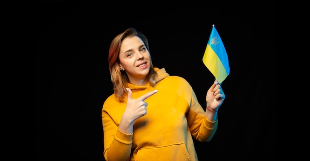 Drapeau national de l'Ukraine Belle fille ukrainienne avec le drapeau du gouvernement sur un bâton dans ses mains sur fond noir Symbole de l'État ukrainien