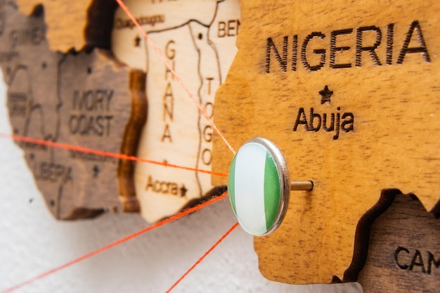 Le drapeau nigérian sur la broche avec un fil rouge montrait les chemins sur la carte en bois