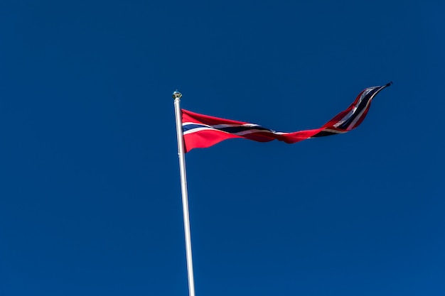 Drapeau norvégien contre le ciel bleu, drapeau de la Norvège