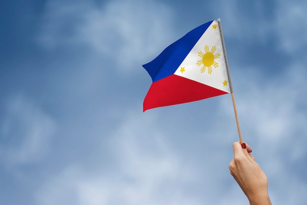 Photo drapeau philippin contre le ciel avec des nuages