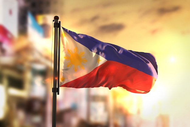 Drapeau des Philippines contre la ville Contexte flou au Sunrise Backlight