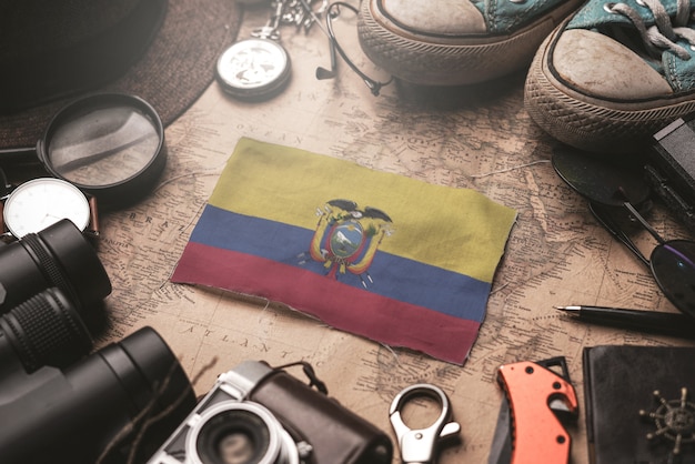 Drapeau de l'Équateur entre les accessoires du voyageur sur l'ancienne carte vintage. Concept de destination touristique.