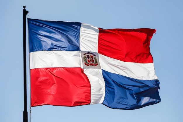 Drapeau de la république dominicaine agitant contre un ciel bleu clair gros plan isolé