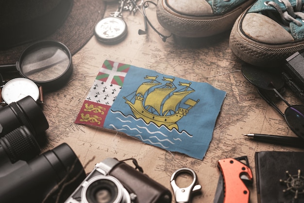 Drapeau Saint Pierre et Miquelon entre les accessoires du voyageur sur l'ancienne carte vintage. Concept de destination touristique.