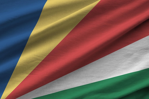 Drapeau des Seychelles avec de grands plis agitant de près sous la lumière du studio à l'intérieur des symboles officiels a