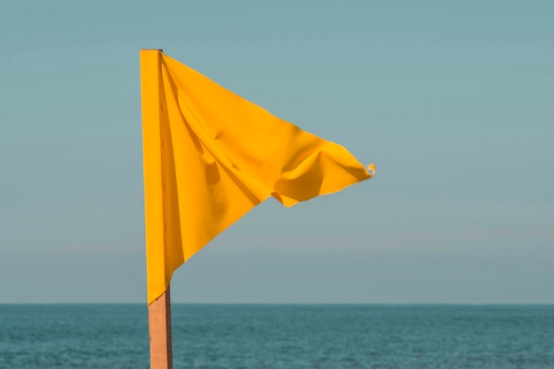 Drapeau de signal d'avertissement de marée haute agitant sur la plage