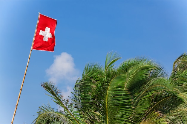 Drapeau suisse dans le vent sur un fond de ciel bleu gros plan extrême.