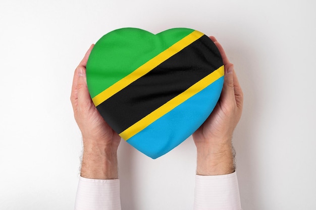 Drapeau de la Tanzanie sur une boîte en forme de coeur dans les mains d'un homme fond blanc