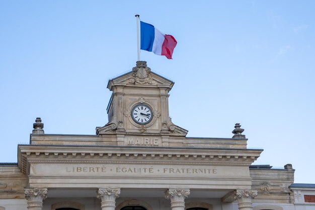 Drapeau tricolore français sur le bâtiment du texte de la mairie signifie l'hôtel de ville dans le centre-ville avec l'horloge en France