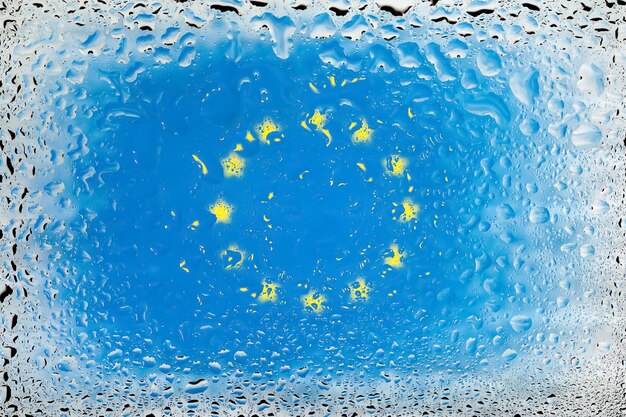 Drapeau de l'UE Drapeau de l'Union européenne sur fond de gouttes d'eau Drapeau avec gouttes de pluie Éclaboussures sur verre