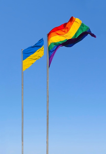 Drapeau L'Ukraine et les drapeaux LGBT flottent dans le vent contre le ciel bleu