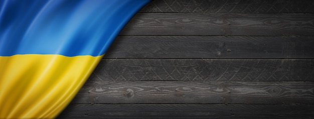 Drapeau de l'Ukraine sur le mur en bois noir. panoramique.