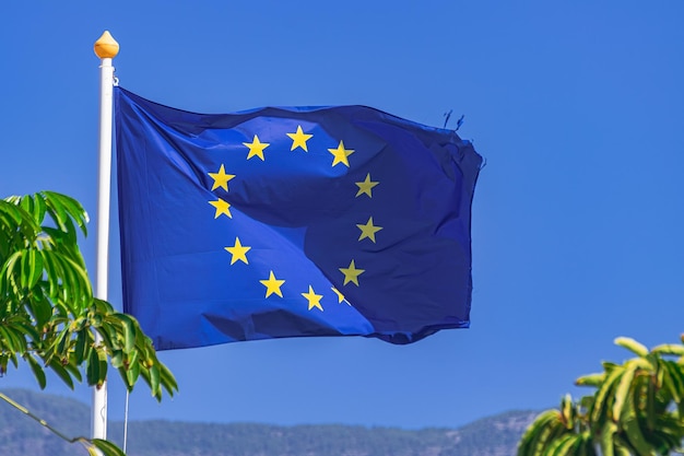 Le drapeau de l'Union européenne agitant avec la lumière du soleil et le ciel bleu en arrière-plan