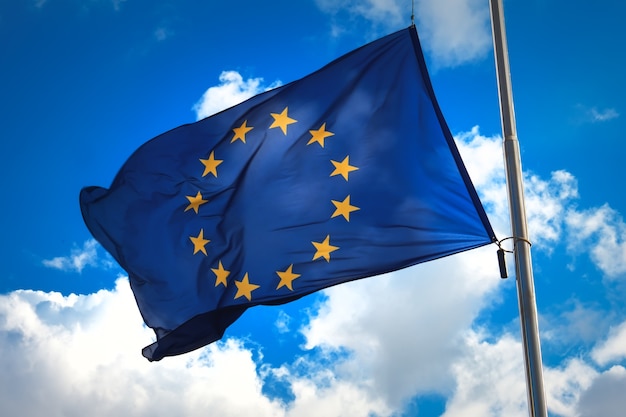 Drapeau De L'union Européenne Contre Un Ciel Bleu Nuageux. Le Symbole Officiel De L'ue.