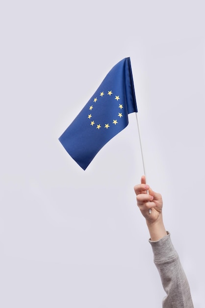 Drapeau de l'Union européenne dans la main de l'enfant sur fond blanc Cadre vertical