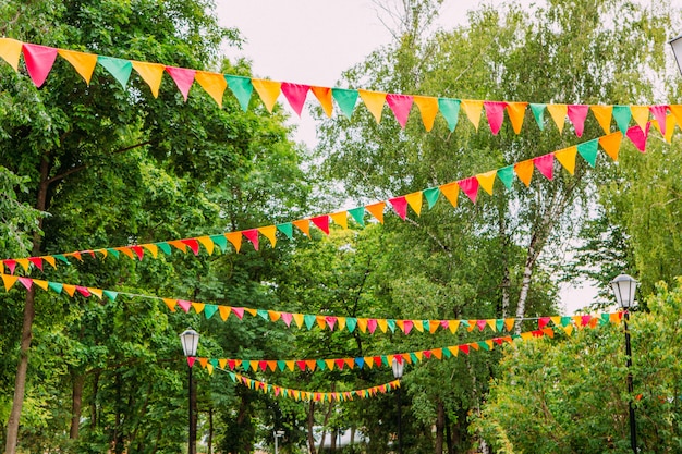 Photo drapeaux de fête suspendus à l'extérieur par une belle journée d'été. décorations de drapeaux colorés pour la fête