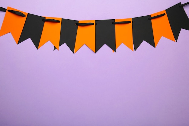 Drapeaux de fête vierges et oranges pour la décoration d'Halloween sur fond violet. Vue de dessus