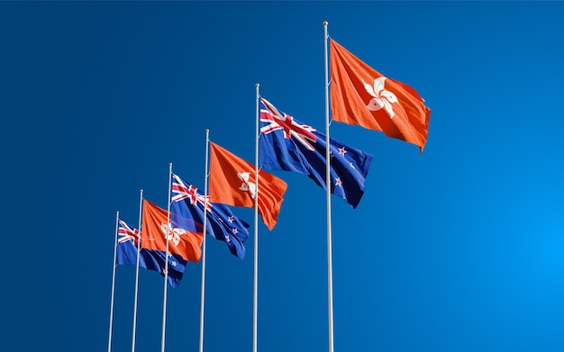 Les drapeaux de la Nouvelle-Zélande et de Hong Kong volent ensemble dans le vent contre le ciel bleu