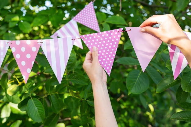 Drapeaux triangulaires d'une belle couleur rose sur fond de jardin verdoyant Décor festif le concept de célébrer un anniversaire de vacances