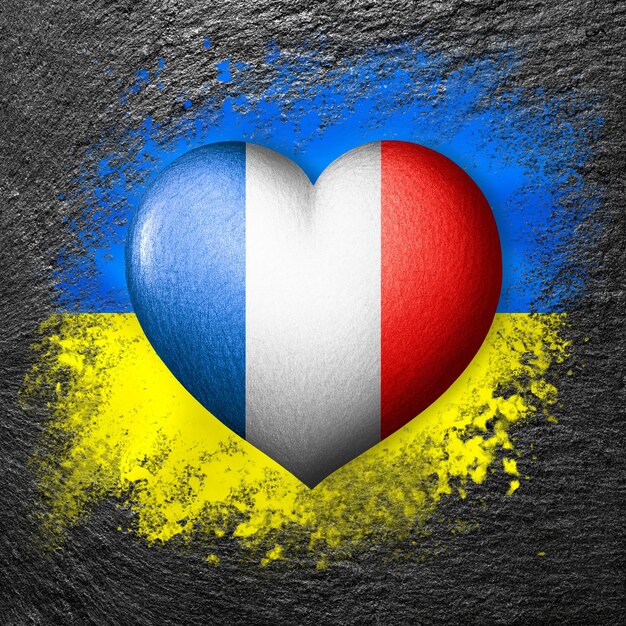 Drapeaux de l'Ukraine et de la France Coeur de drapeau sur le fond du drapeau de l'Ukraine peint sur une pierre