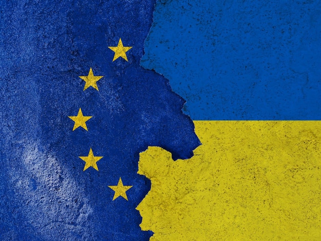 Drapeaux de l'Union européenne et de l'Ukraine sur le ciment fissuré du vieux fond de texture de mur Bannière européenne avec un long grunge de fissure de pierre dans un bâtiment industriel abandonné à l'extérieur sur la rue de la ville ukrainienne