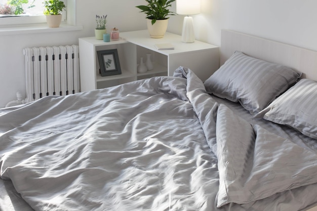 Draps gris au soleil sur le lit dans la chambre