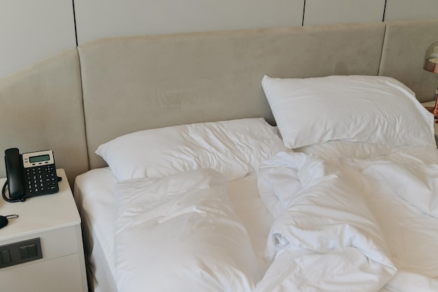 Draps et oreillers défaits Lit désordonné défait après un concept de sommeil confortable