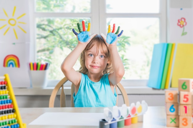 Photo drôle beau garçon heureux enfant montre les mains sales avec de la peinture enfant dessine en riant avec de la peinture