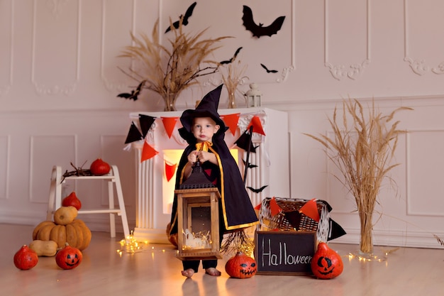 Drôle de bébé garçon en costume de sorcière d'halloween avec jack citrouille et balai à l'intérieur