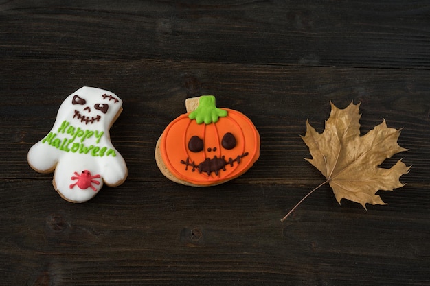 Drôle de citrouille d'Halloween faite maison et biscuits fantômes Fond en bois à côté des feuilles d'automne