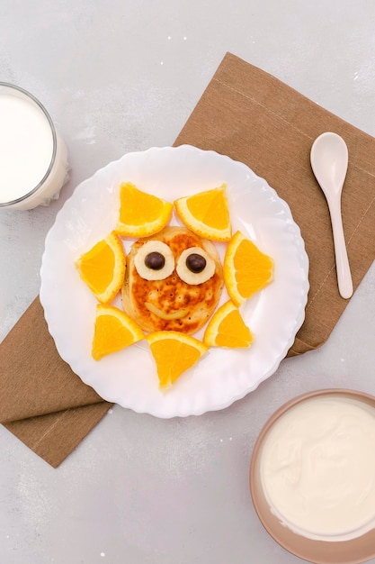 Drôle de collation en forme de visage de soleil de crêpeorange sur assiette