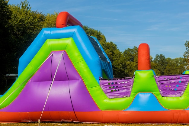 Drôle dans un château gonflable glisse sur un parcours d'obstacles coloré dans l'aire de jeux