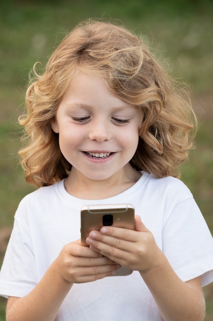 Drôle enfant aux cheveux longs tenant un téléphone portable