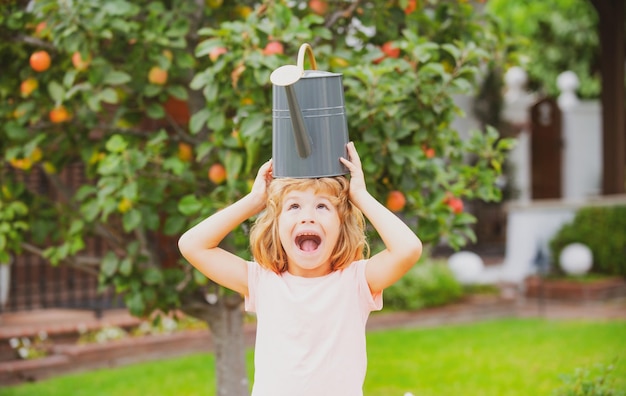 Drôle enfant excité arrose les plantes dans le jardin avec arrosoir