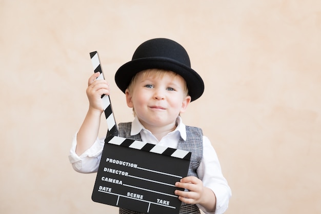 Drôle enfant tenant clap. Heureux enfant s'amusant à la maison. Concept de cinéma rétro