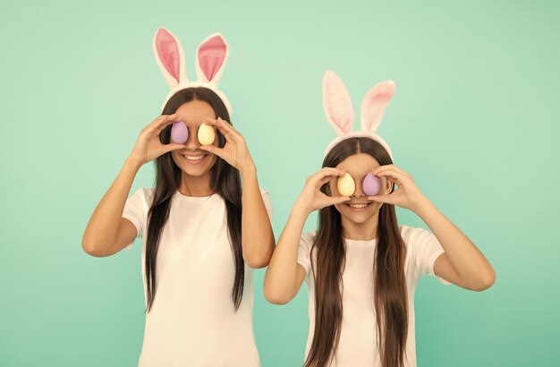 Drôle de famille de pâques de mère et fille dans des oreilles de lapin tenant des oeufs peints chasse aux oeufs de pâques