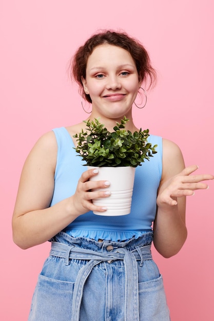 Drôle de fille dans un t-shirt bleu et un short un arrière-plan isolé de pot de fleurs inchangé