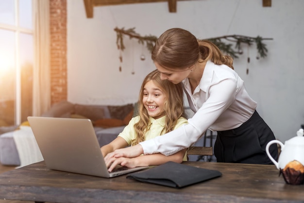 Photo drôle de fille rire avec sa mère et son ordinateur à la maison