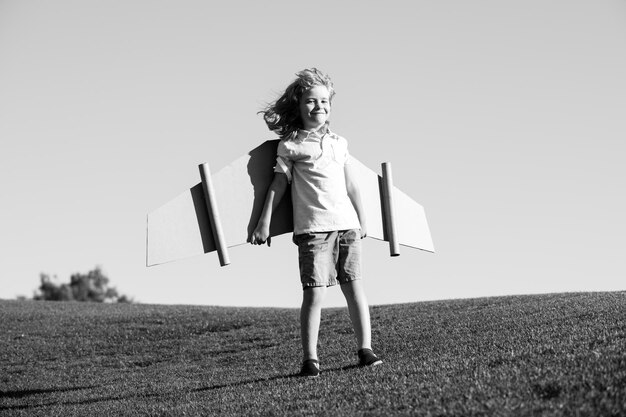 Drôle de garçon avec des ailes d'avion en carton jouet voler concept de liberté de démarrage enfant portant un costume d'aviateur