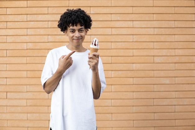 Drôle d'homme africain aux cheveux bouclés tenant un cornet de crème glacée et pointant le doigt dessus